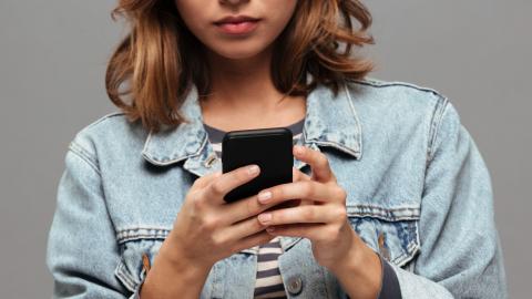 A young girl holding a smartphone with her face obscured.